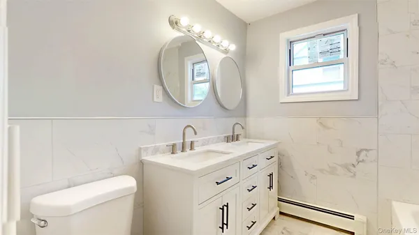a bathroom with a toilet a sink a mirror and a window