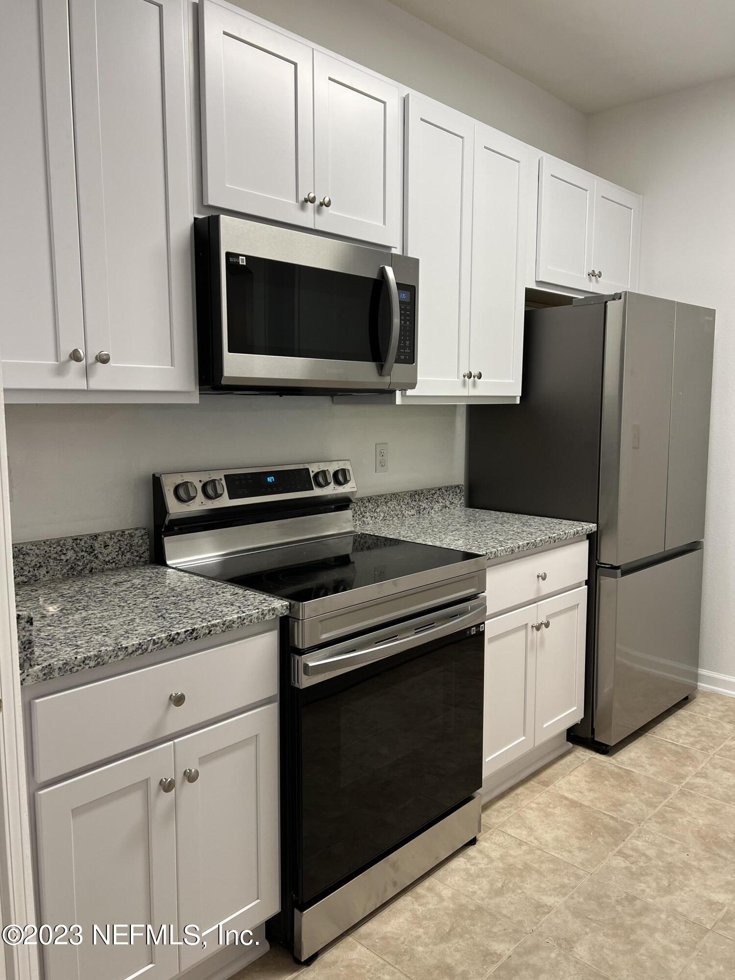 7990 Baymeadows Road East, Unit 418 Jacksonville, FL 32256 - Photo 11 of 25 a kitchen with granite countertop white cabinets and stainless steel appliances