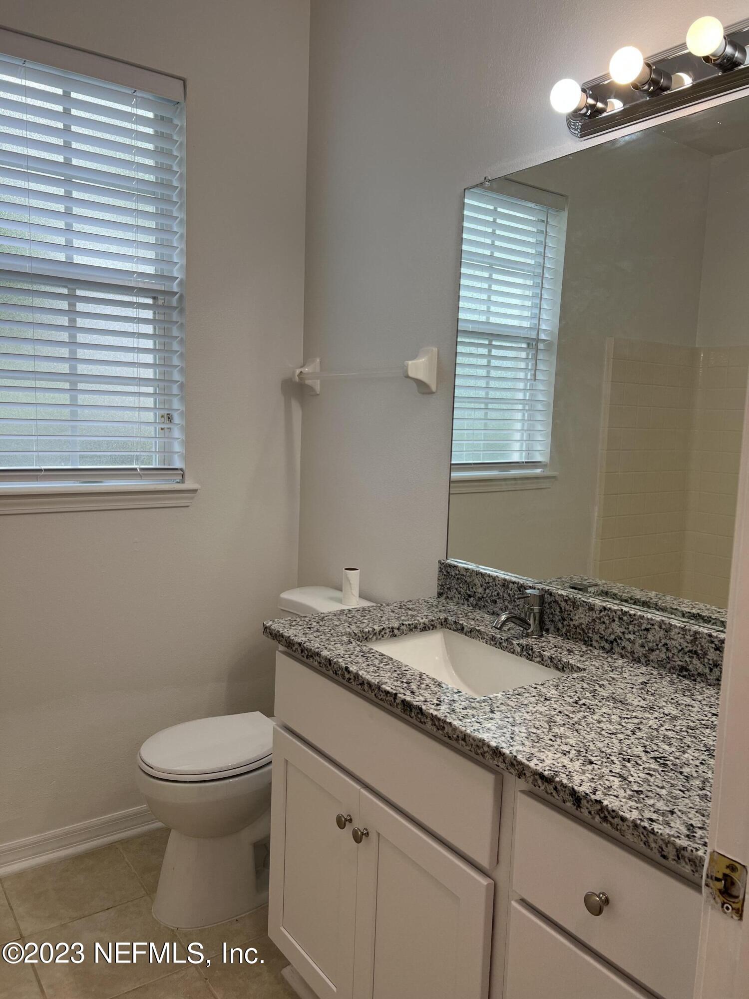 7990 Baymeadows Road East, Unit 418 Jacksonville, FL 32256 - Photo 18 of 25 a bathroom with a granite countertop toilet a sink and a window