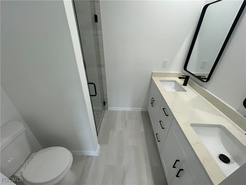 453 Bell Boulevard Lehigh Acres, FL 33974 - Photo 13 of 21 a bathroom with a sink a toilet a mirror and shower