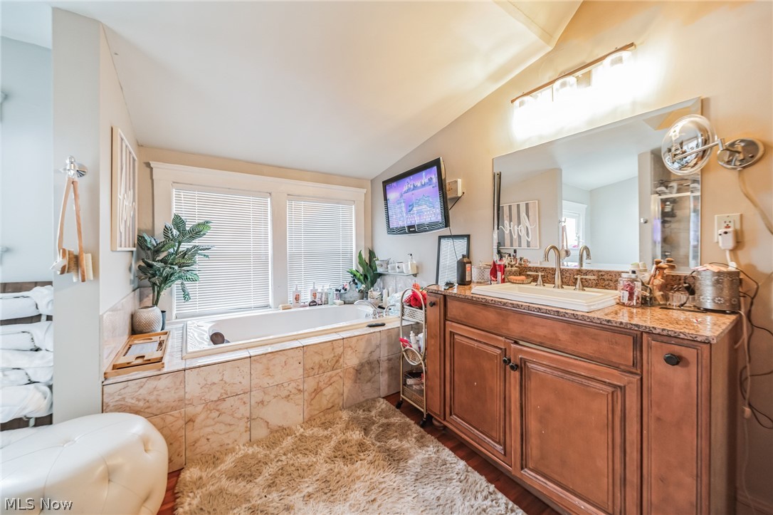 14432 Superior Road Cleveland, OH 44118 - Photo 5 of 24 Bathroom with a relaxing tiled bath, lofted ceiling, vanity with extensive cabinet space, and hardwood / wood-style floors