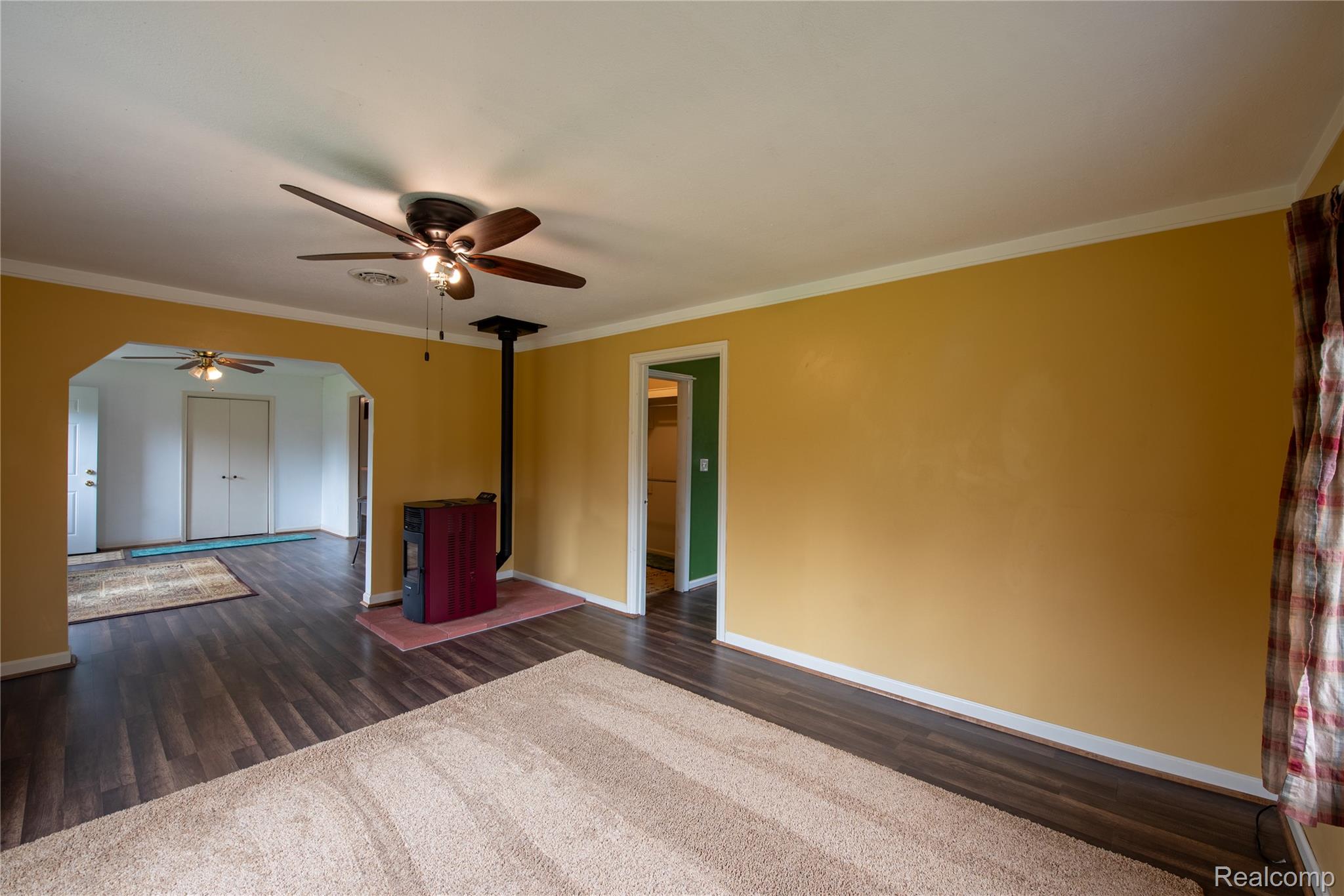 1190 Meadow Road Tawas City, MI 48763 - Photo 5 of 26 Unfurnished room featuring a ceiling fan, dark wood-style floors, ornamental molding, and arched walkways