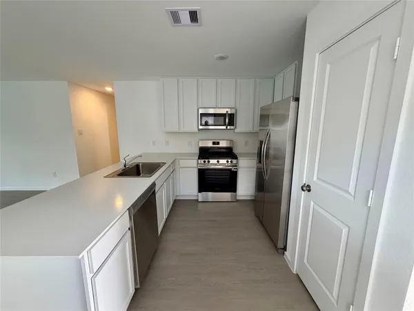 a kitchen with refrigerator cabinets and wooden floor