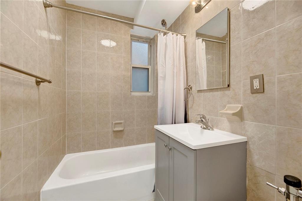 9411 Shore Road, Unit 1A Brooklyn, NY 11209 - Photo 13 of 19 a bathroom with a sink a mirror and a bathtub
