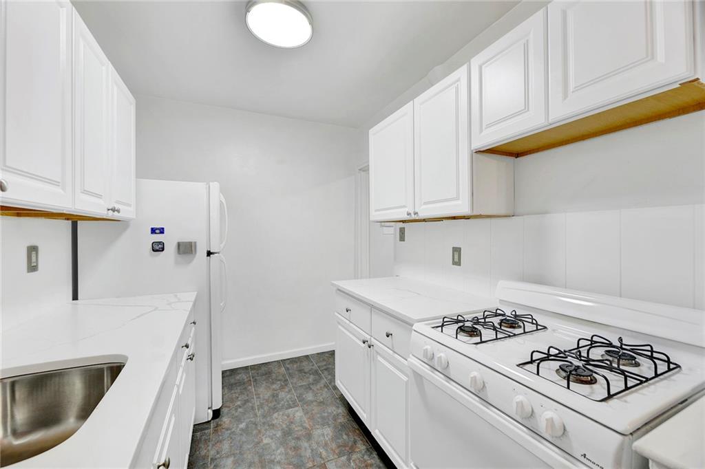 9411 Shore Road, Unit 1A Brooklyn, NY 11209 - Photo 4 of 19 a kitchen with stainless steel appliances white cabinets a stove a sink and a white refrigerator