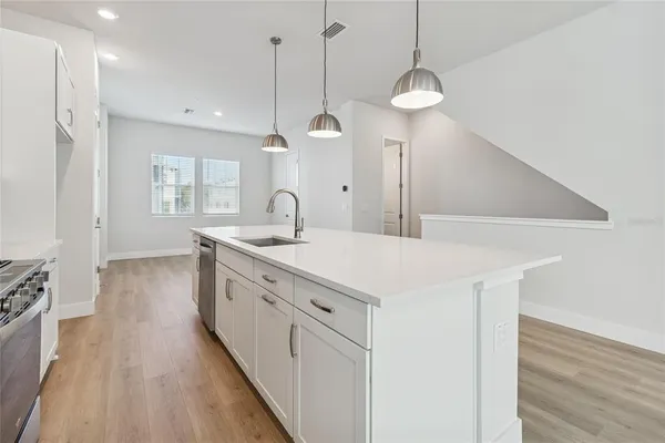 a kitchen with stainless steel appliances granite countertop a sink a stove and a wooden floors