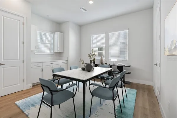 a large white kitchen with white cabinets and wooden floors