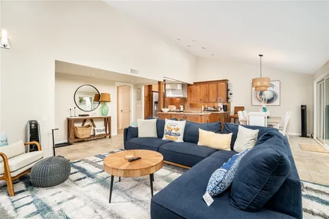 a living room with furniture kitchen view and a chandelier