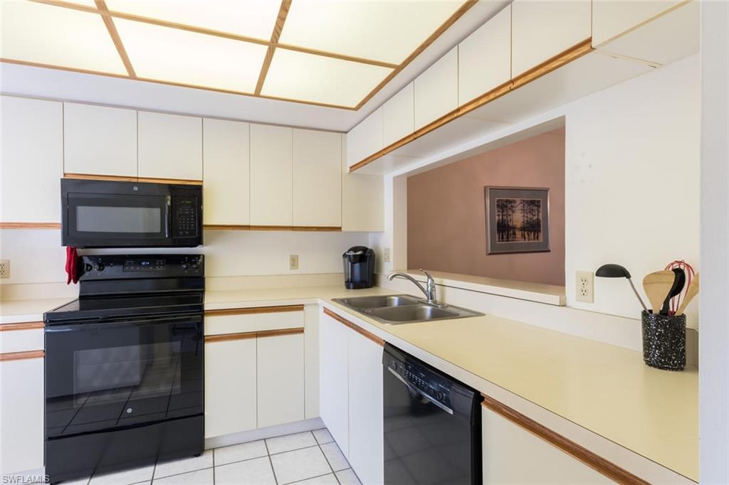 4973 Pepper Circle, Unit F105 Naples, FL 34113 - Photo 11 of 20 a kitchen with a sink and a stove top oven with wooden floor