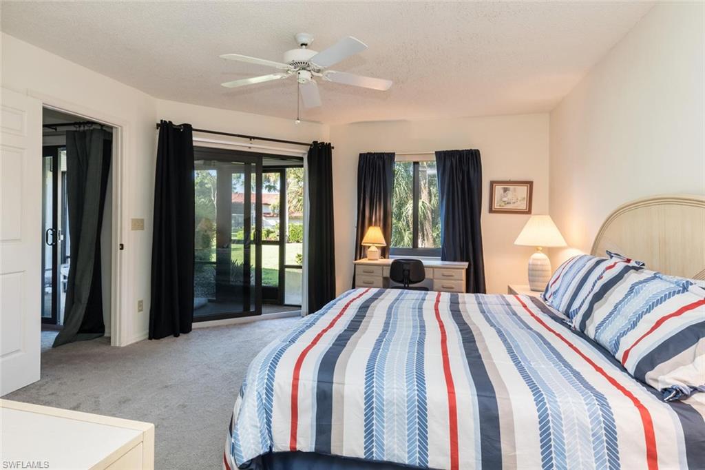 4973 Pepper Circle, Unit F105 Naples, FL 34113 - Photo 13 of 20 a bedroom with a large bed and a chandelier