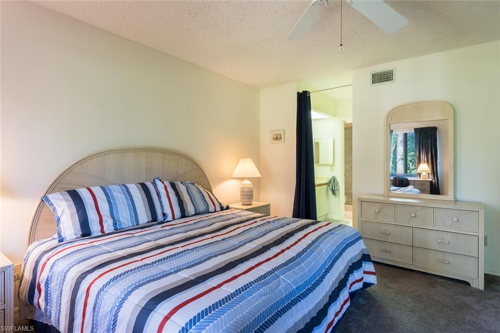 4973 Pepper Circle, Unit F105 Naples, FL 34113 - Photo 14 of 20 a bedroom with a bed and a large mirror