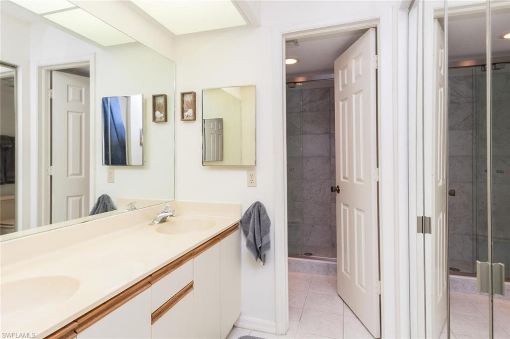 4973 Pepper Circle, Unit F105 Naples, FL 34113 - Photo 15 of 20 a bathroom with a tub sink and mirror