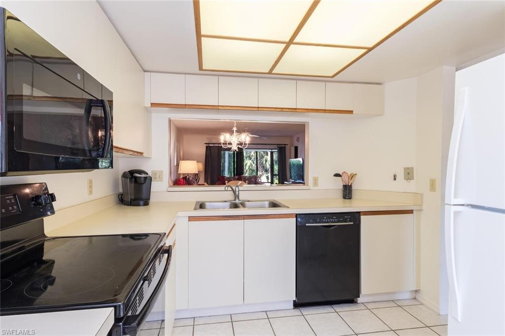4973 Pepper Circle, Unit F105 Naples, FL 34113 - Photo 10 of 20 a kitchen with a sink a stove top oven and cabinets