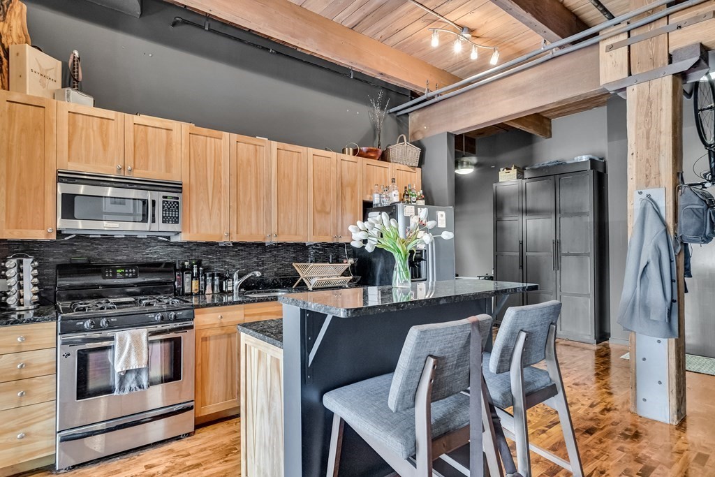 210 Broadway, Unit 103 Everett, MA 02149 - Photo 9 of 16 a kitchen with stainless steel appliances kitchen island granite countertop a stove a sink and a refrigerator