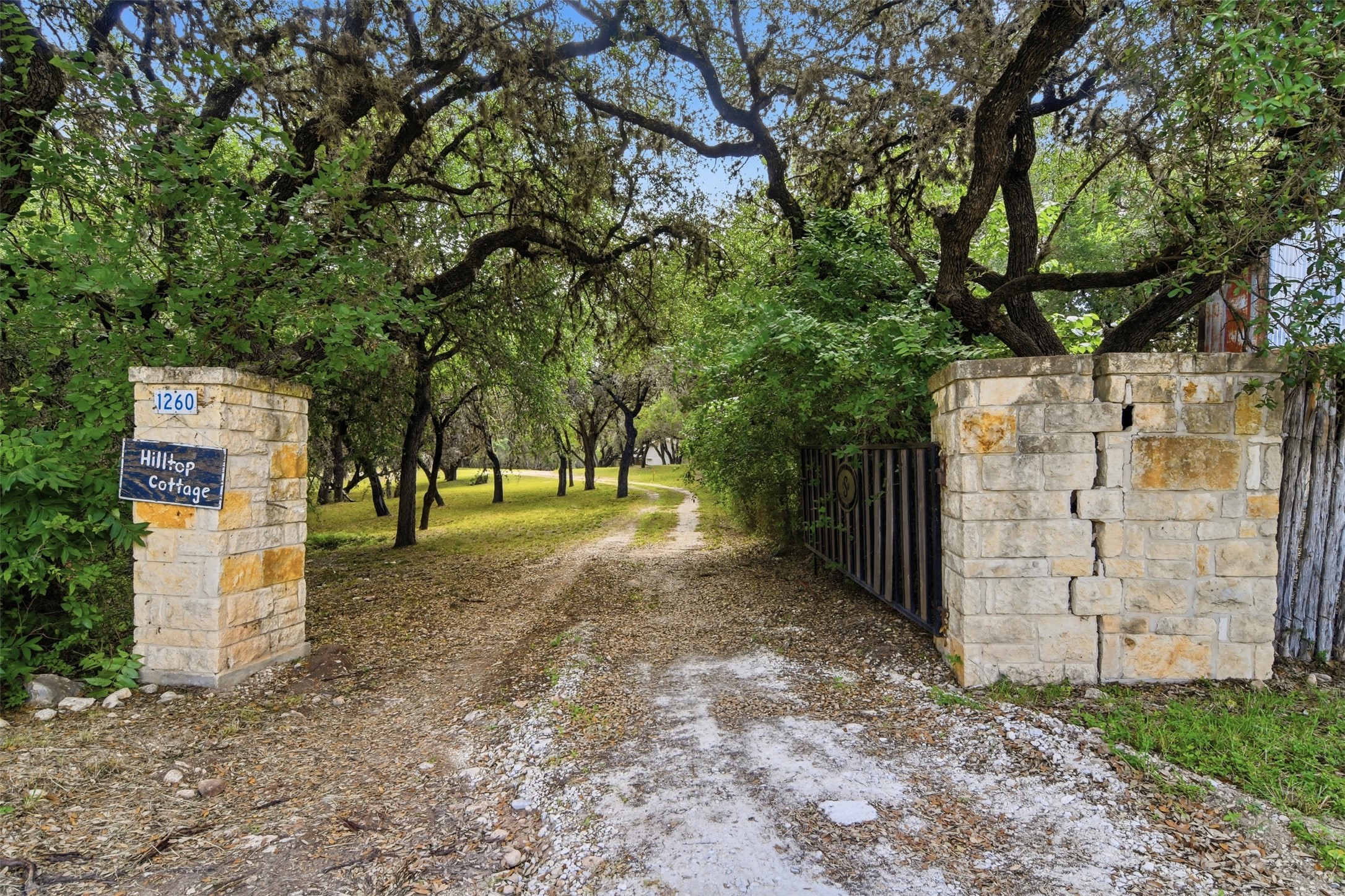 1260 Magers Road Concan, TX 78838 - Photo 28 of 40 A stone-columned entry gate marks the private, tree-lined driveway leading to a secluded cottage.