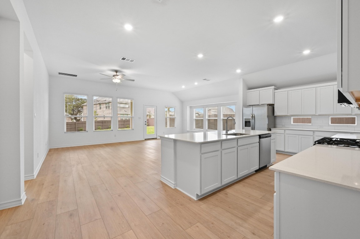 1613 Dove Rnch Road Georgetown, TX 78628 - Photo 28 of 29 a large white kitchen with kitchen island a sink a center island and stainless steel appliances