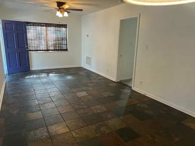 an empty room with kitchen view and natural light