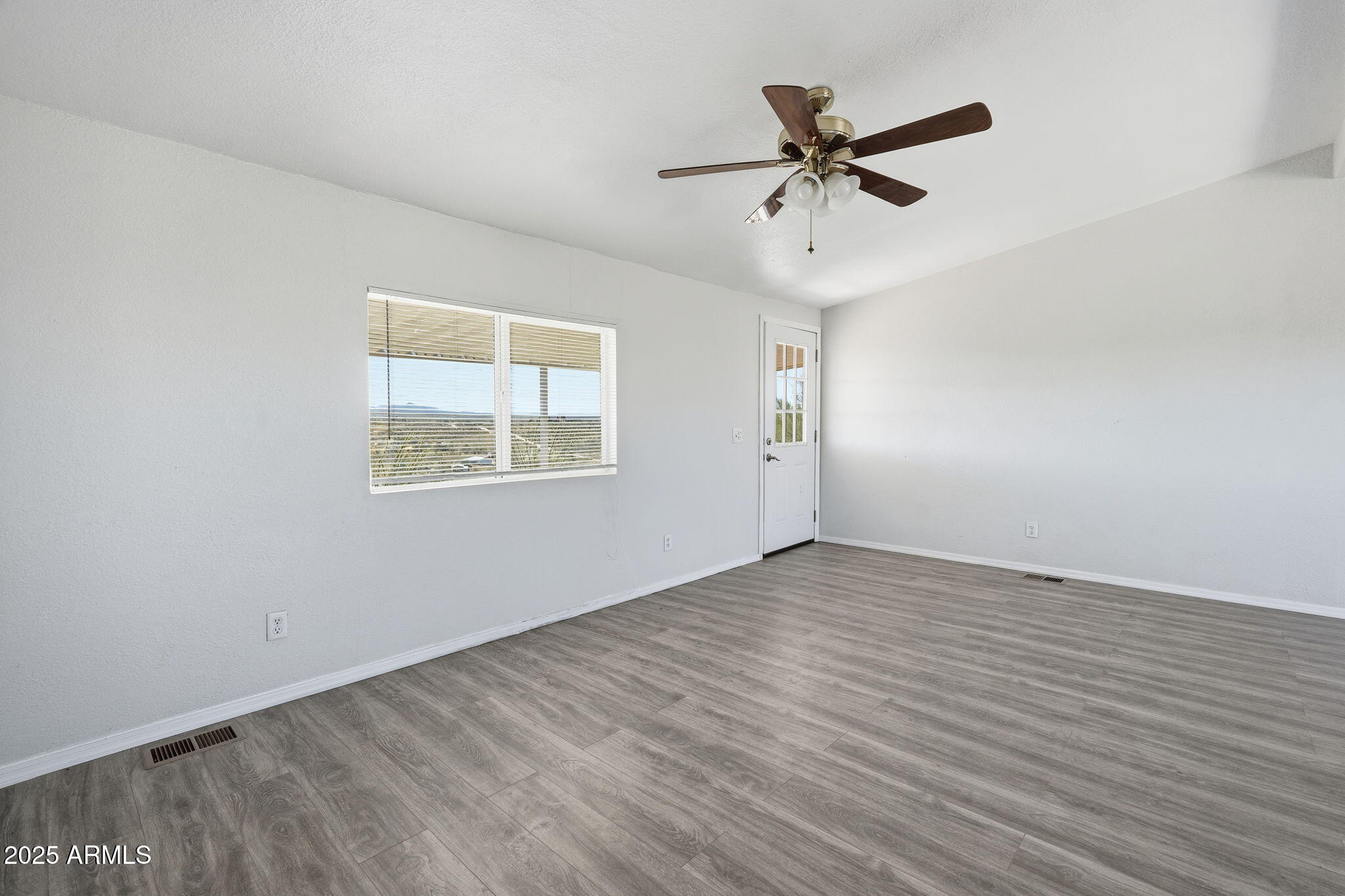 25100 East Lori Road Benson, AZ 85602 - Photo 11 of 30 an empty room with wooden floor ceiling fan and windows