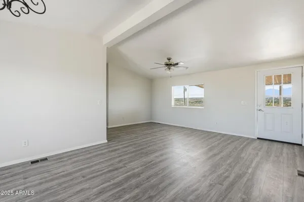 an empty room with wooden floor chandelier fan and windows