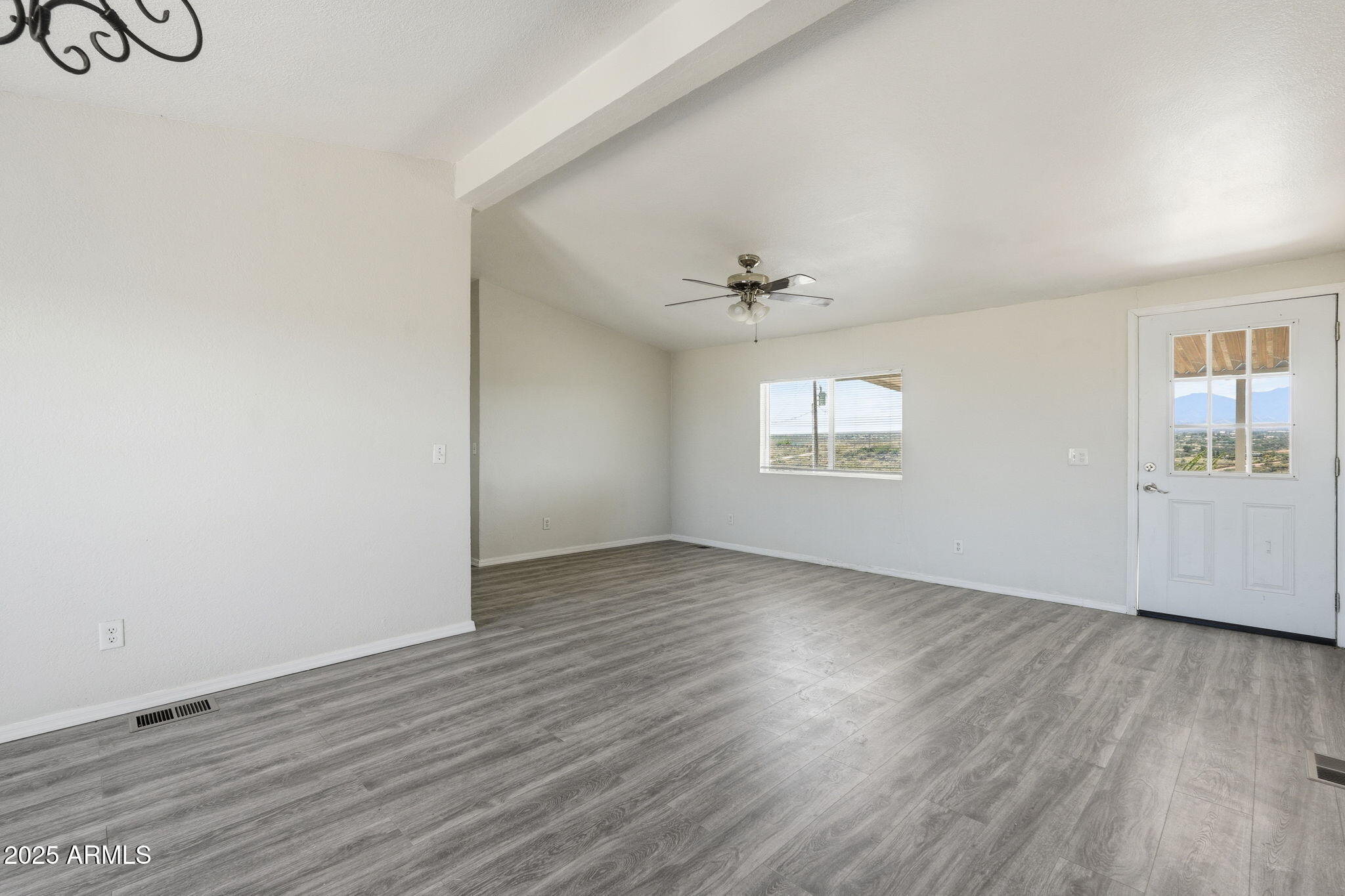 25100 East Lori Road Benson, AZ 85602 - Photo 6 of 30 an empty room with wooden floor chandelier fan and windows