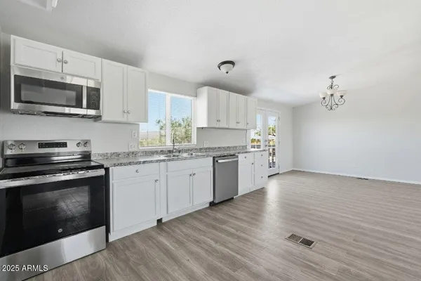 a kitchen with stainless steel appliances granite countertop a stove top oven a sink dishwasher and a microwave oven on the wooden floor