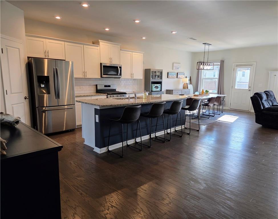3042 Lowell Road Bethlehem, GA 30620 - Photo 9 of 49 a kitchen with stainless steel appliances granite countertop a refrigerator a stove top oven a sink dishwasher a dining table and chairs with wooden floor