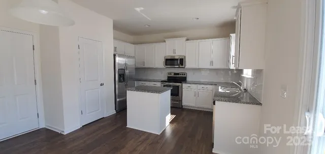 a kitchen with a refrigerator a stove top oven a sink and a hard wood floor