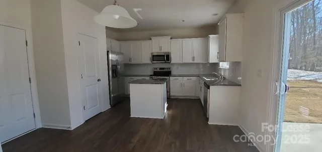 a kitchen with stainless steel appliances granite countertop a refrigerator a sink dishwasher and a stove with wooden floor