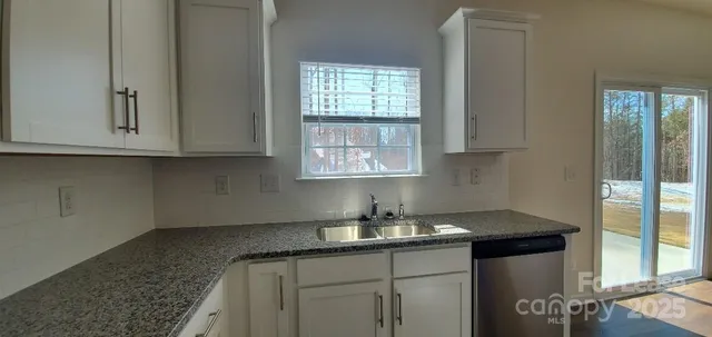 a kitchen with granite countertop white cabinets and a sink