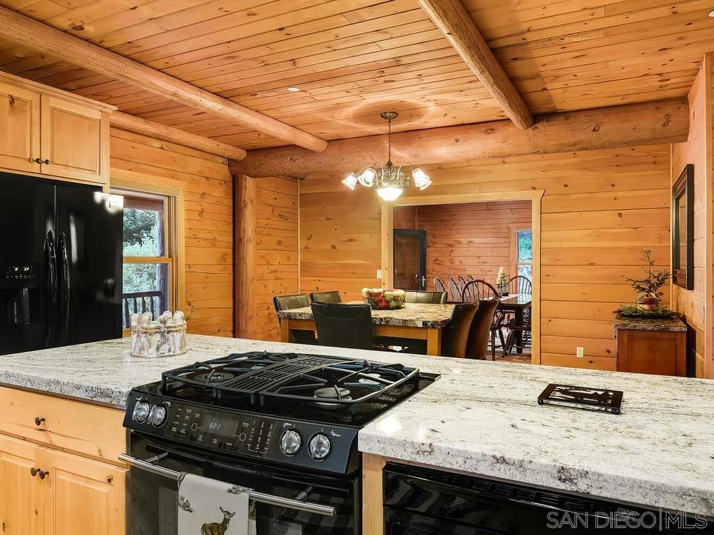 1068 West Incense Cedar Road Julian, CA 92036 - Photo 28 of 63 a kitchen with granite countertop a stove and a wooden cabinets