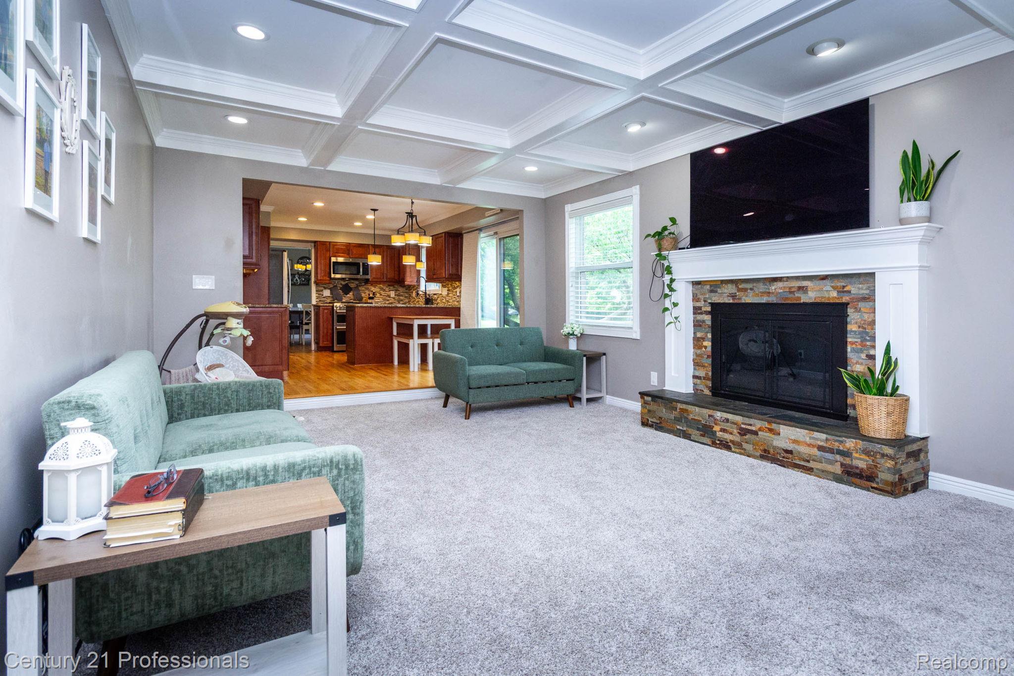 671 Bridgestone Drive Rochester, MI 48309 - Photo 17 of 50 Living area featuring a coffered ceiling with recessed lighting, a fireplace with a stacked stone facade and white mantel, and light-toned carpeting