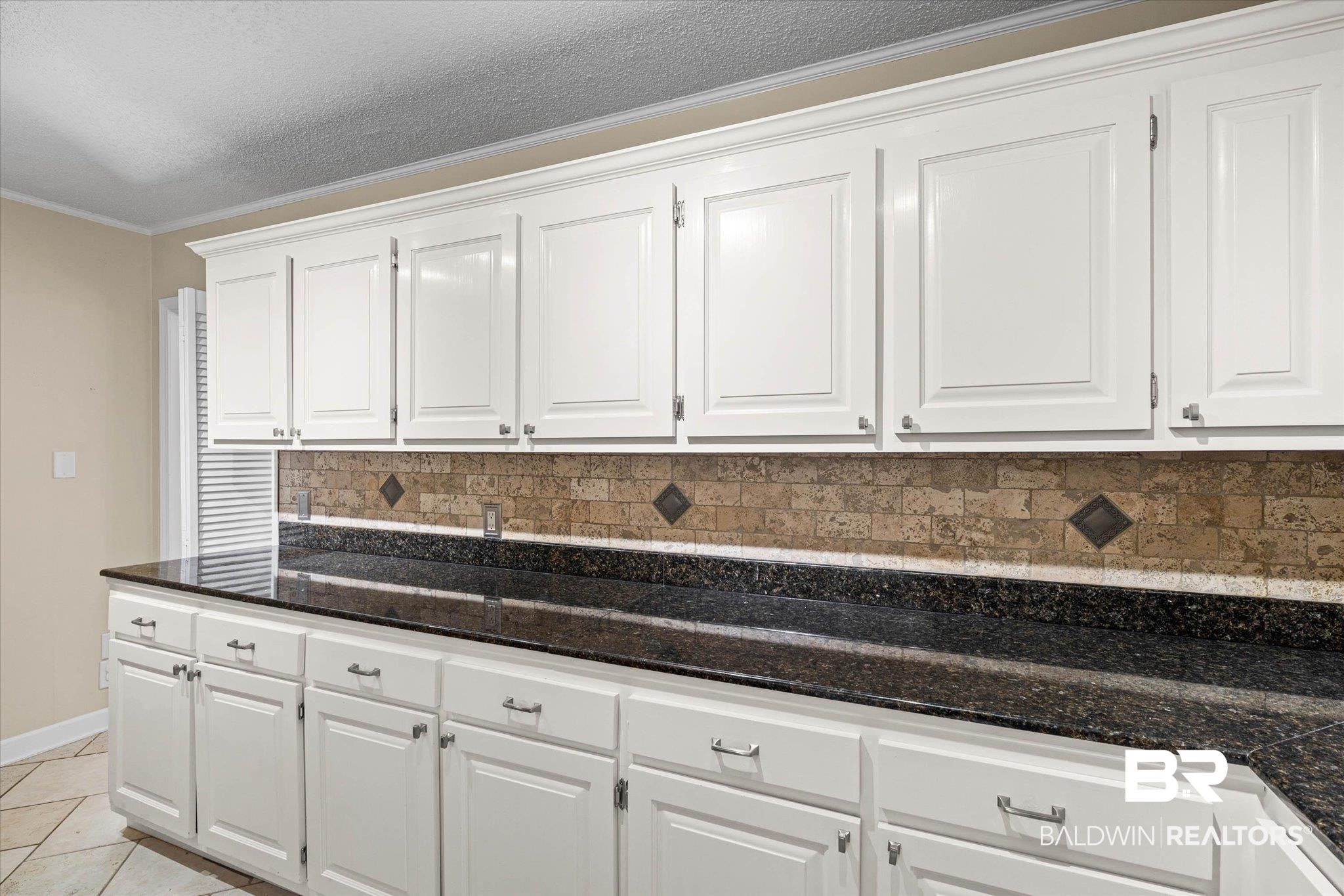 3724 Claridge Road South Mobile, AL 36608 - Photo 14 of 42 Kitchen featuring white cabinets, backsplash, ornamental molding, dark stone counters, and light tile patterned floors