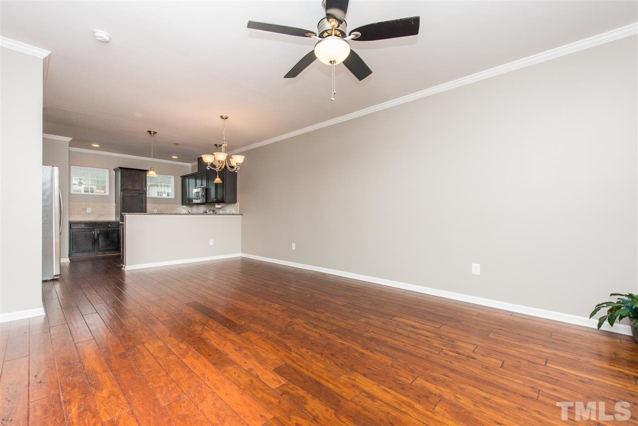 1433 Crafton Way Raleigh, NC 27607 - Photo 4 of 23 an empty room with wooden floor and a kitchen view