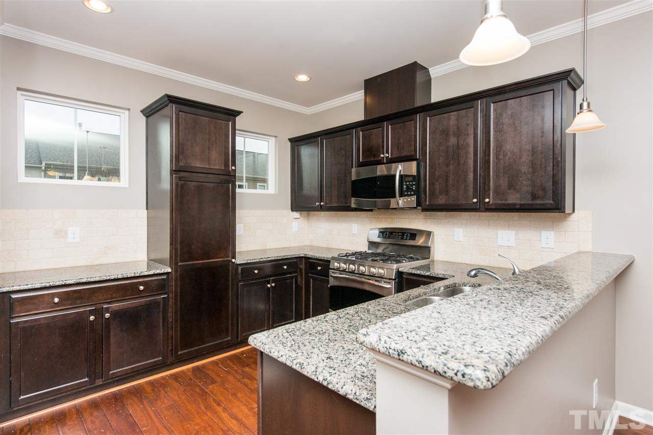 1433 Crafton Way Raleigh, NC 27607 - Photo 6 of 23 a kitchen with granite countertop wooden cabinets a stove top oven and refrigerator