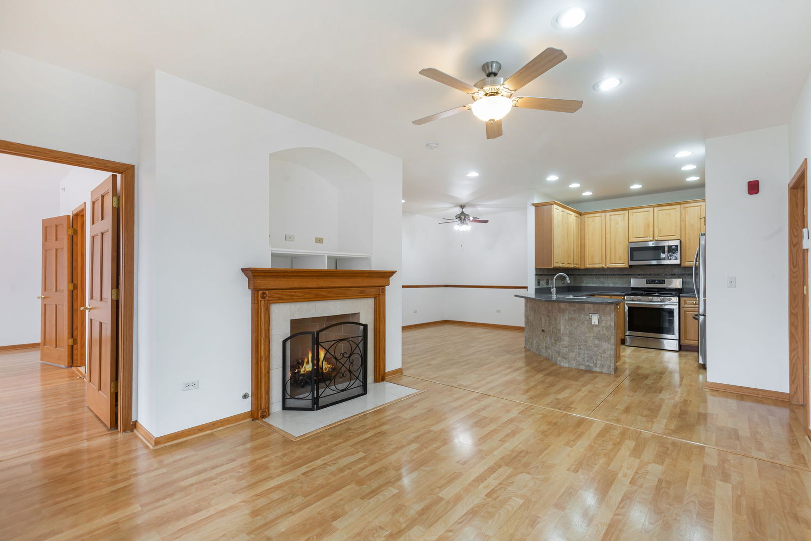1259 West Lake Street, Unit 203 Addison, IL 60101 - Photo 6 of 17 a view of a kitchen with a stove a fireplace a ceiling fan and wooden floor