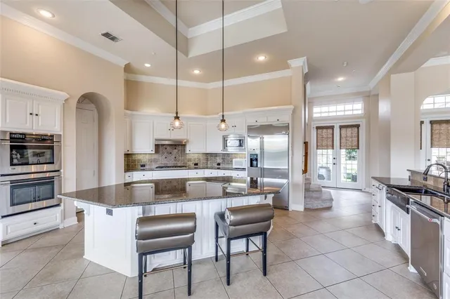 a kitchen with kitchen island granite countertop a stove a sink a oven a dining table and chairs