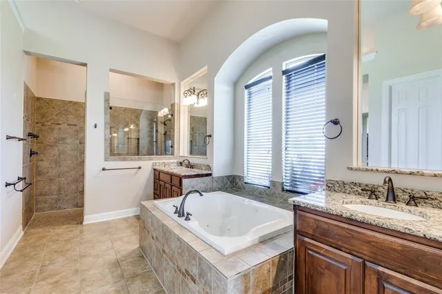 a bathroom with a granite countertop tub sink and mirror