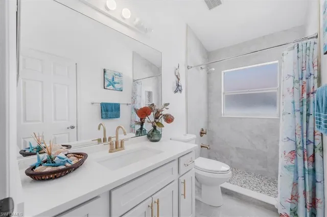 a bathroom with a granite countertop sink a toilet and shower