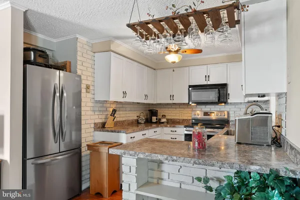 a kitchen with stainless steel appliances granite countertop a refrigerator a stove a sink dishwasher and a microwave with wooden floor