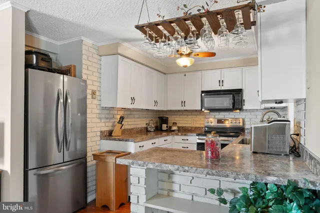 a kitchen with stainless steel appliances granite countertop a refrigerator a stove a sink dishwasher and a microwave with wooden floor