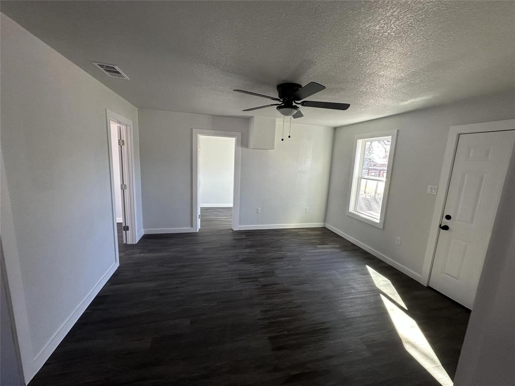 401 Walker Street Glen Rose, TX 76043 - Photo 3 of 10 an empty room with wooden floor and windows