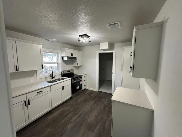 a kitchen with a sink a counter top space stainless steel appliances and cabinets