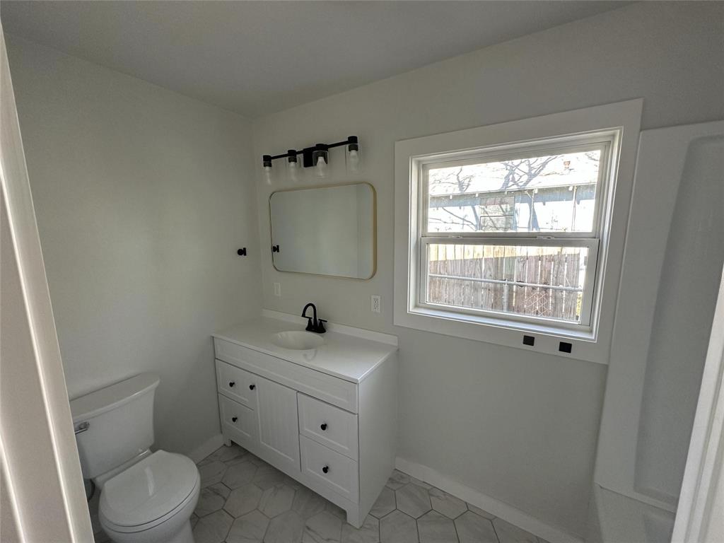 401 Walker Street Glen Rose, TX 76043 - Photo 8 of 10 a bathroom with a toilet sink a window and mirror
