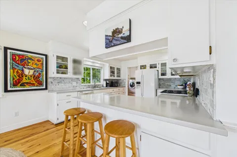 a kitchen with stainless steel appliances granite countertop a stove top oven a sink dishwasher a dining table and chairs with wooden floor