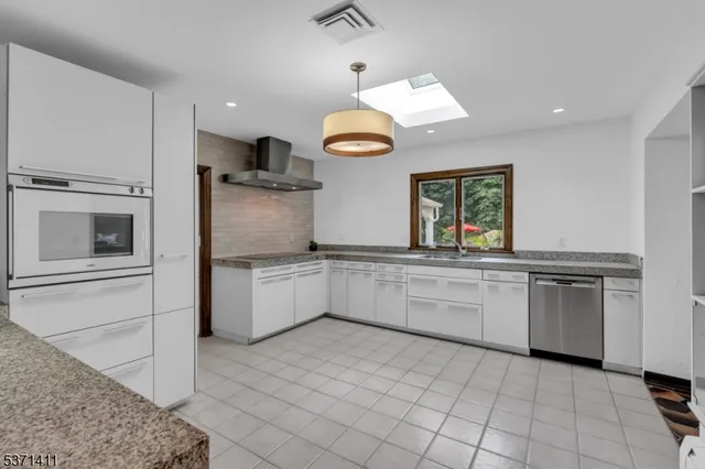 a kitchen with granite countertop white cabinets and stainless steel appliances