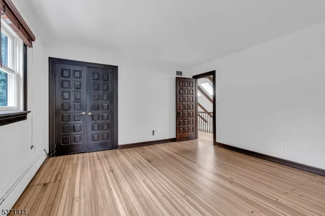 a view of an empty room with wooden floor and windows