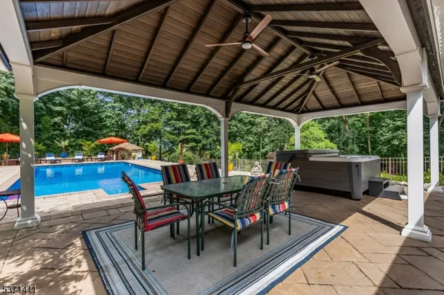 a view of a patio with table and chairs under an umbrella with a barbeque grill
