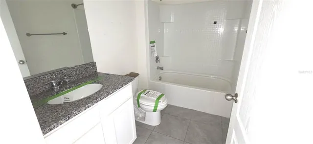 a bathroom with a granite countertop bathtub sink and toilet