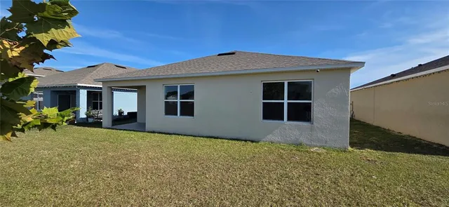 a front view of house with yard and trees in the background