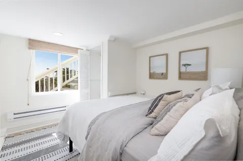 a bedroom with a white bed and a painting on the wall